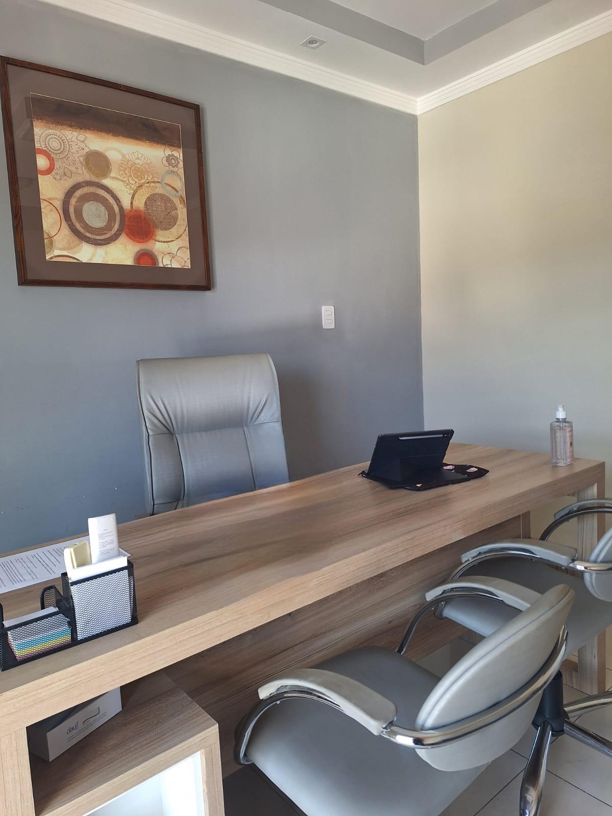Sala de espera do consultório, com duas poltronas e uma mesa de apoio